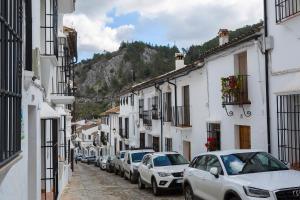 eine Reihe von Autos, die auf einer Straße mit Gebäuden geparkt sind in der Unterkunft Paco del Molino in Grazalema