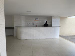 a man standing behind a counter in a room with white tiles at Porto Marina in Salvador +37 photos