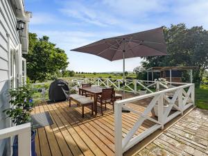 een houten terras met een tafel en een parasol bij Cosy Guesthouse in Tranquil Puriri, Thames in Thames