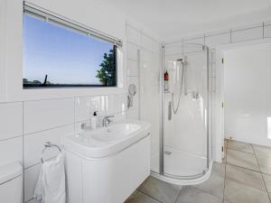 een witte badkamer met een wastafel en een douche bij Cosy Guesthouse in Tranquil Puriri, Thames in Thames
