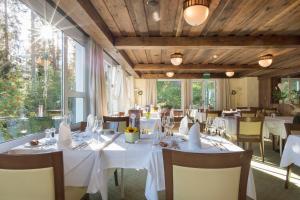 a restaurant with white tables and chairs and windows at Sunstar Hotel Arosa in Arosa
