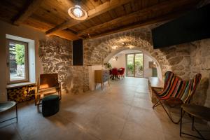 a living room with a stone wall and chairs at Villa Nika - Rustic Stone House with Heated Pool in Rasopasno