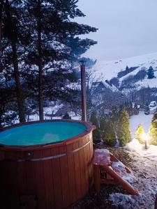 a hot tub with a view of a snowy mountain at Domek Sielski Zakątek Pieniny in Szczawnica