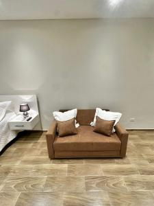 un canapé marron dans une pièce avec un mur blanc dans l'établissement Modern studio apartment in Asunción, à Asuncion
