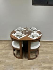 - une table en bois avec des chaises, des assiettes et des verres à vin dans l'établissement Modern studio apartment in Asunción, à Asuncion