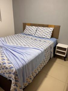 un letto con coperta blu e bianca e comodino di Sossego Potiguar a Parnamirim