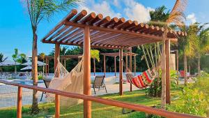 a hammock under a wooden pergola next to a pool at Sossego Potiguar in Parnamirim