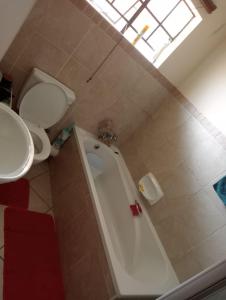 een badkamer met een bad, een toilet en een wastafel bij Fairway Gardens in Pretoria