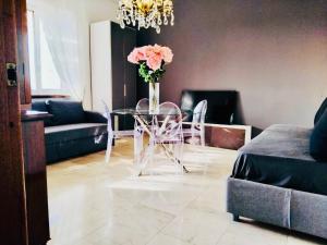 een eetkamer met een glazen tafel met een vaas met bloemen bij Charming Central Relais in Bergamo