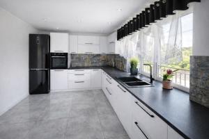 a kitchen with white cabinets and a black refrigerator at Dom u Teresy in Harkabuz +12 photos