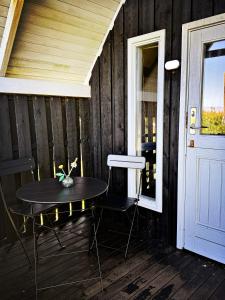 Una mesa y sillas en un porche con puerta. en Bovbjerg Camping, en Lemvig