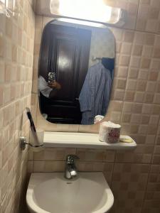 a bathroom sink with a mirror and a person taking a picture at Fadilimmo Bsa app 201 in Yaoundé