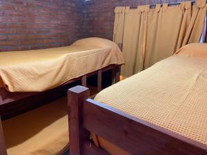 trois lits dans une pièce avec un mur de briques dans l'établissement Lucero de Brochero, à Villa Cura Brochero