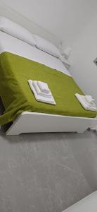 ein Bett mit einer grünen Decke und zwei weißen Handtüchern in der Unterkunft Affittacamere Domus Roseto in Roseto Capo Spulico