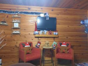 a room with two red chairs and a television at Vikendica Rajvosa Vlašić in Šišava