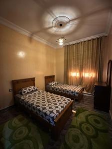 a bedroom with two beds and a television in it at ZAHA Appart in Ksar es Sghir