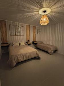 een slaapkamer met 2 bedden en een kroonluchter bij Dunas de Arena in La Porteña