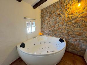a bath tub in a room with a stone wall at La Casa del Pastor 1890 in Benaocaz +68 photos
