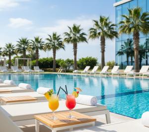 una piscina con sedie a sdraio e cocktail sui tavoli di fronte a un hotel di Takes Antalya Luxury Hotel a Antalya (Adalia)