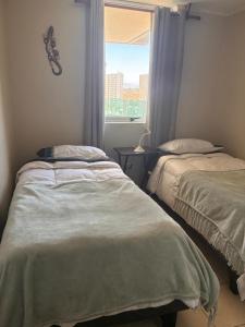 a bedroom with two beds and a window at Depto playa herradura in Coquimbo
