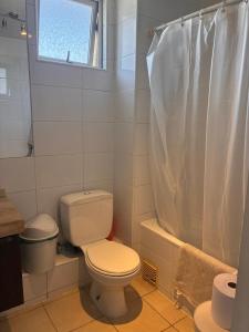 a white bathroom with a toilet and a shower at Depto playa herradura in Coquimbo +1 photo