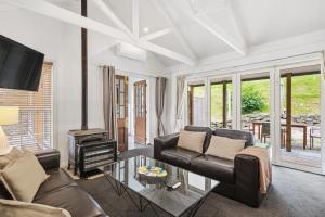 een woonkamer met een leren bank en een open haard bij Arrow Junction Cottage in Arrowtown