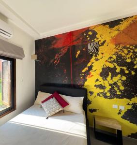 a bedroom with a bed with a painting on the wall at Club Ébène Ouidah in Ouidah