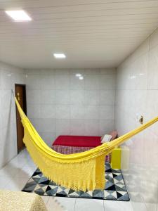 un'amaca gialla in una stanza con un letto rosso di Kitnet 1 ambiente a Campina Grande