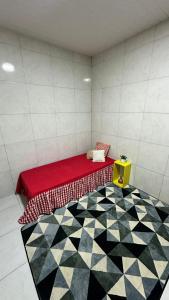 una stanza con un letto rosso e un pavimento a scacchi di Kitnet 1 ambiente a Campina Grande