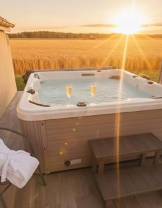 a hot tub with glasses of wine in a field at Domaine des Hirondelles - Escapade de Charme & Spa à 15min de Provins in Champcenest