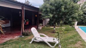 une chaise blanche assise dans l'herbe près d'une piscine dans l'établissement Departamento en Sinsacate, à Sinsacate