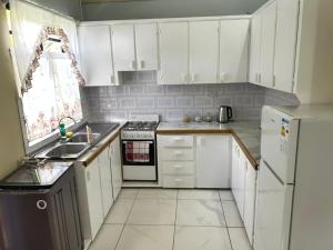 a kitchen with white cabinets and a sink and a refrigerator at C's Sunrise Escape in Roseau