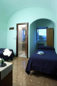 een blauwe slaapkamer met een bed en een raam bij Oasi Francescana il Monastero in Vicovaro