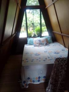 een bed in een kleine kamer met een raam bij Chalé Garças in Chapada dos Guimarães +2 foto's