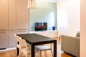 een eetkamer met een zwarte tafel en witte stoelen bij Ca' Borsa IV - Suite con balcone in pieno centro in Treviso