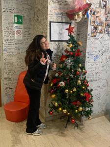 uma mulher ao lado de uma árvore de Natal em Lion University & Youth Hostel Milano em Milão