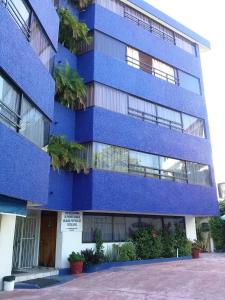 a blue building with plants in front of it at Suites Menavi in Acapulco