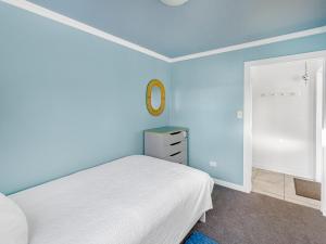 een blauwe slaapkamer met een bed en een spiegel bij Cosy Guesthouse in Tranquil Puriri, Thames in Thames