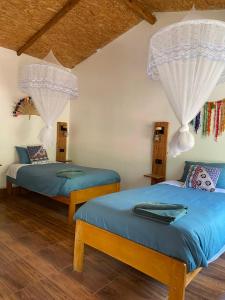 2 Betten in einem Zimmer mit weißen Wänden und Holzböden in der Unterkunft Eco Terra Lodge in Santa María