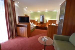 um quarto de hotel com televisão e sala de estar em Hotel Coellner Hof em Colônia