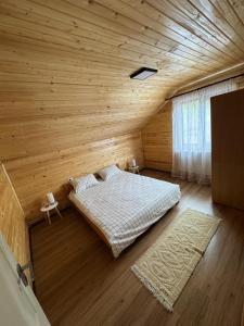 una camera da letto con un letto in una stanza di legno di Casa Diana a Huedin