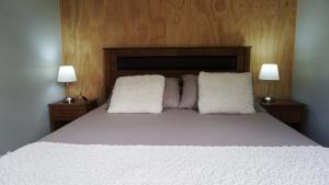 a bed with two white pillows and two lamps at Lodge Perry Barnes in Puerto Varas