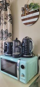 een magnetron bovenop een blauwe plank met apparaten bij Hydrangea Cottage in Marton in Marton +2 foto's