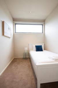 Un dormitorio con una cama blanca y una ventana. en Moments to Sand on Bear, en Mordialloc