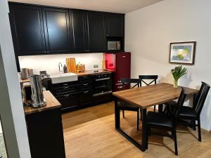 une cuisine avec des armoires noires, une table et des chaises dans l'établissement Travelers Studio, à Njarðvík