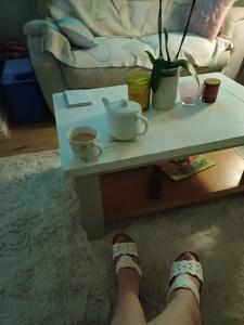 eine Person, die ihre Füße auf einem Couchtisch mit Tassen abgelegt hat in der Unterkunft Little town house in Birkenhead