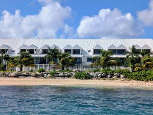a large white house on the beach with the ocean at Pearl View Condo in Baie Nettle