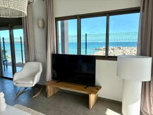 a living room with a television and a table and a chair at Pearl View Condo in Baie Nettle