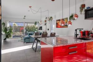 eine Küche mit roten Schränken und ein Wohnzimmer in der Unterkunft Saillon, maison 5 pers - Terrasse - Parking privé in Saillon