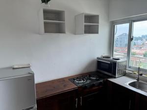 eine kleine Küche mit Herd und Mikrowelle in der Unterkunft Appartement 1 chambre a Bacongo in Brazzaville